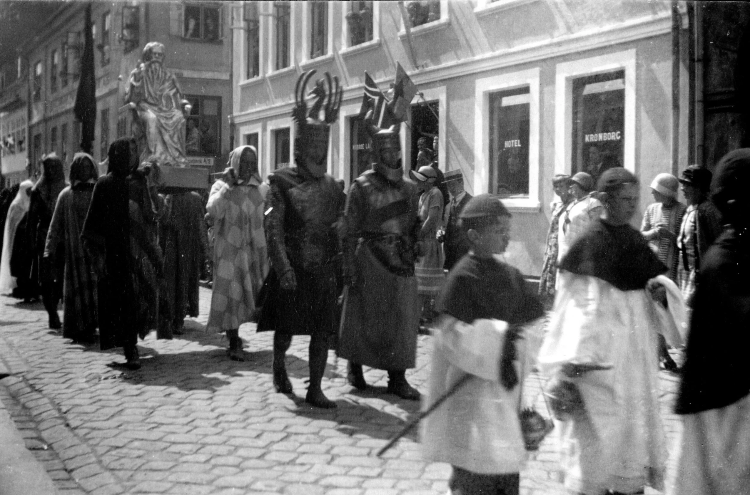 57.428 Messedrengene med røgelseskarrene. Bagved ses statue af Hellig hertug Knud. Det er ved Strandgade 47, Hotel Kronborg.