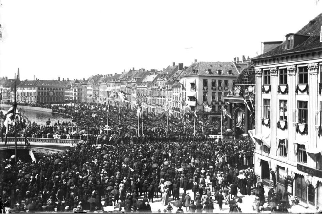 22.18 Billede fra Christian IX guldbryllup i 1892, d. 26 maj. Menneskemængden kigger på kareterne, som kører over Højbro, til portalen som er opstillet i anledning af guldbrylluppet, der hvor statuen af Biskop Absalon i dag står.