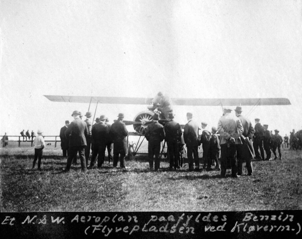 70.227 Et N og W Aeroplan påfyldes benzin på flyvepladsen ved Kløvermarken. Flyet er bygget af den københavnske maskinfabrik Nielsen og Winther der i 1916 oprettede en aeroplanafdeling. I 1917 blev der leveret 6 fly af typen N og W type Aa til det danske militær.